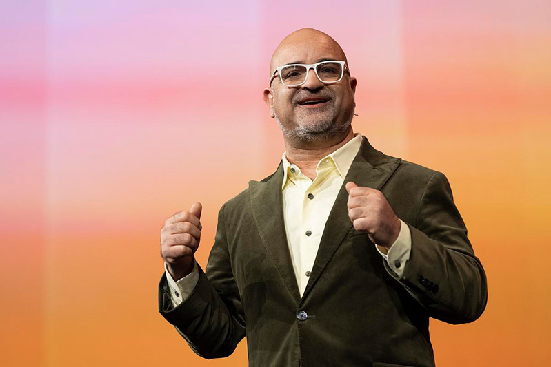A male presenter gesturing with both hands