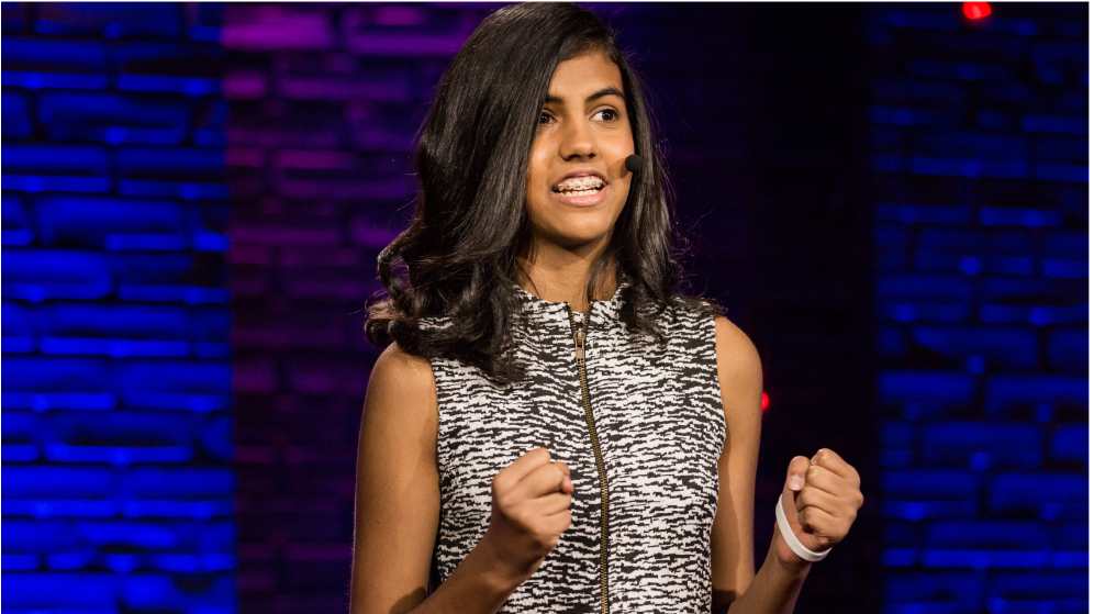 A presenter smiles, with fists raised