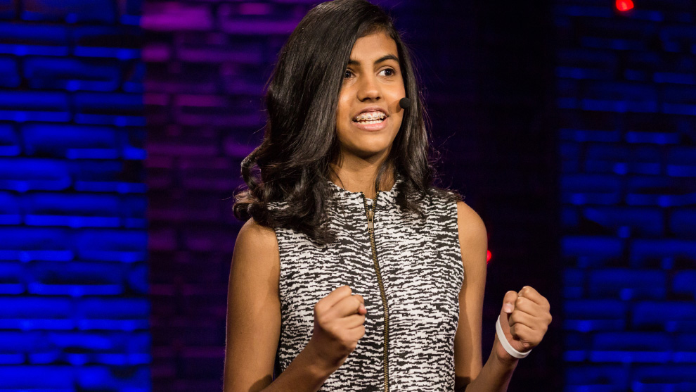A presenter smiles, with fists raised